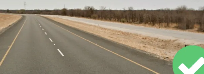 ¿En qué país una carretera de color gris claro, con aspecto recién pavimentado, corre paralela a una carretera importante hasta una frontera, como esta?